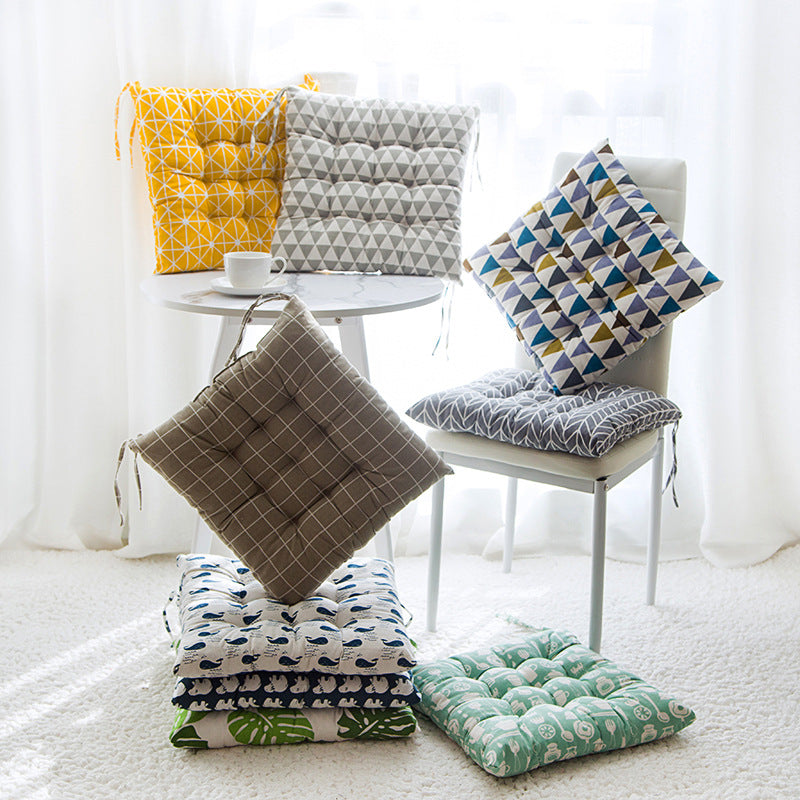 Collection of patterned cushions on chairs and a table in a bright room.