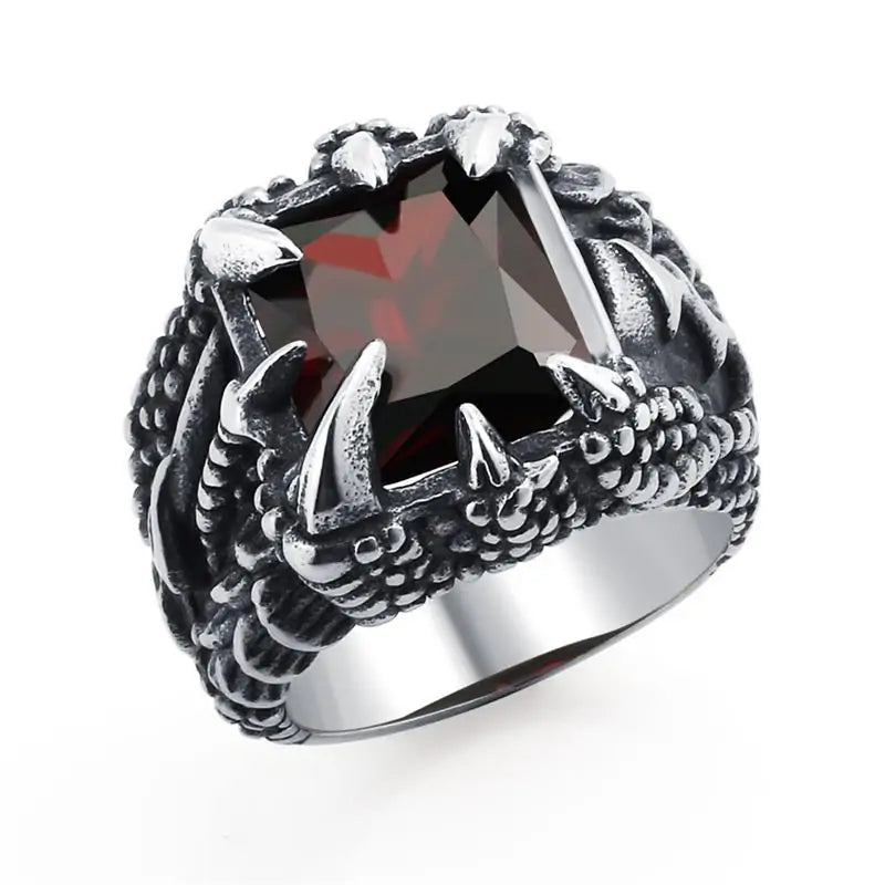 Silver-toned statement ring with a large faceted square red gemstone, held by four prongs, and dark engraved detailing on the sides, shown on a white background.