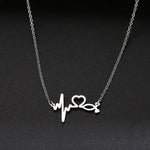 A delicate gold chain necklace featuring a tilted, hollow heart-shaped pendant. The heart is asymmetrically attached at both top curves to the chain, giving it a stylish slant. The background is plain white, highlighting the necklace's elegant and minimalist design.