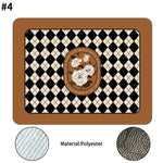 Decorative rectangular polyester mat with a brown border, black and cream diamond pattern, and a central floral emblem featuring white roses, shown with close-up fabric texture details.