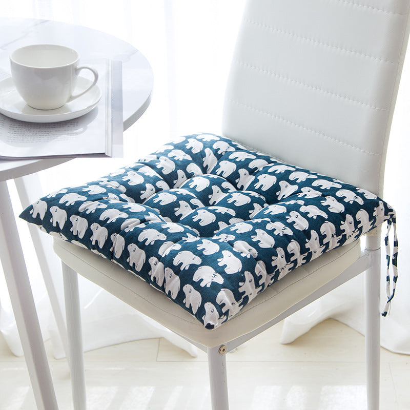 Chair cushion with bear pattern on a chair next to a table with a cup.