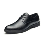 Leather men's dress shoe featuring a subtle crocodile skin texture, closed lacing system, and a low black rubber sole, displayed on a white background.