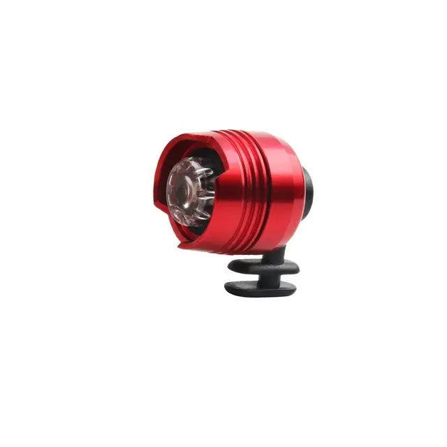 Small red cylindrical LED bike light with a clear front lens, mounted on a black rubber strap, on a white background.