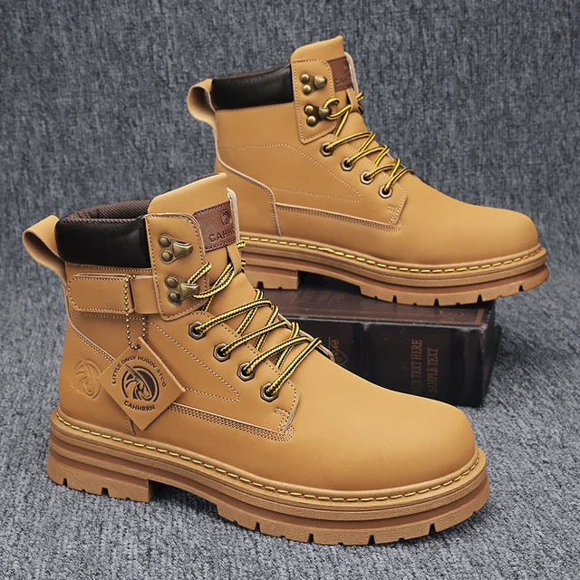 A pair of sleek black leather ankle boots with rugged rubber soles, lace-up fronts, and metal eyelets, displayed on a gray fabric surface with one boot propped up on a vintage-style book for presentation.