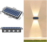 Collage showing a rectangular solar wall light with a blue solar panel and four LED lenses, labeled with dimensions in millimeters, alongside a photo of the light installed outdoors casting upward and downward beams on a wall above grass.