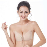 Beige strapless lace-up adhesive bra shown on a smiling model.