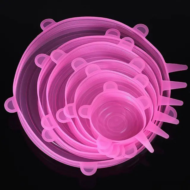Set of translucent pink silicone stretch lids in multiple sizes, stacked together on a black background, each with small pull tabs around the edge.