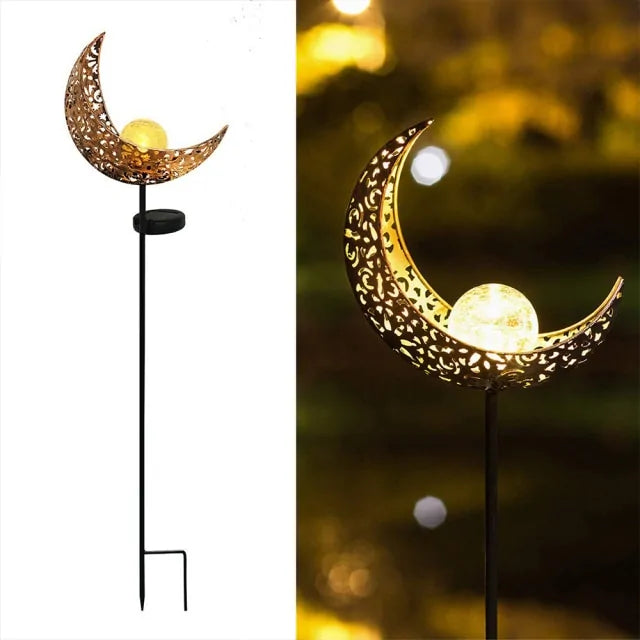 Garden stake light with a decorative gold crescent moon and a glowing orb in the center, shown as a product shot on white (left) and lit up outdoors at night (right).