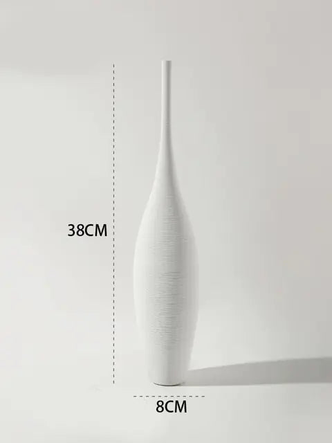 A minimalist product photo of a tall, matte white decorative vase with a narrow neck and elongated body, set against a light grey background. Measurement guides show it is 38 cm tall and 8 cm wide at the base.