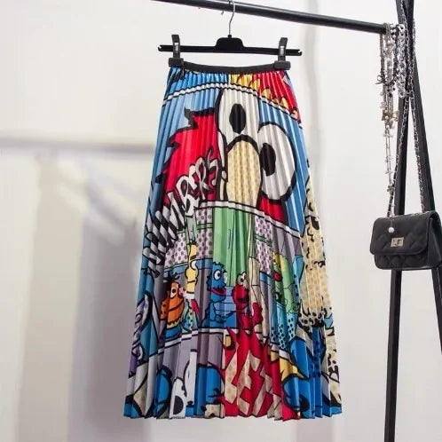 Pleated midi skirt with a gradient design, transitioning from dark black at the waistband to a soft blush pink at the hem, hanging on a black clothing rack next to a vintage-style camera.