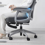 Person relaxing on a gray office chair in a home office setting.