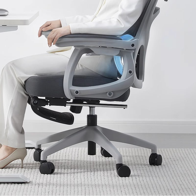 Person relaxing on a gray office chair in a home office setting.