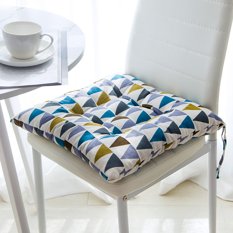 Colorful geometric patterned seat cushion on a chair with a white table and cup in the background.