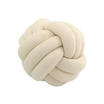 A simple product photo of a cream/off-white knotted cushion shaped like a braided ball. The pillow has thick, soft tubular sections woven into a round knot, shown against a plain white background.