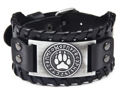 Black braided leather cuff bracelet with snap details and a silver-tone plate featuring a circular emblem with runic-style letters around a paw print, on a white background.