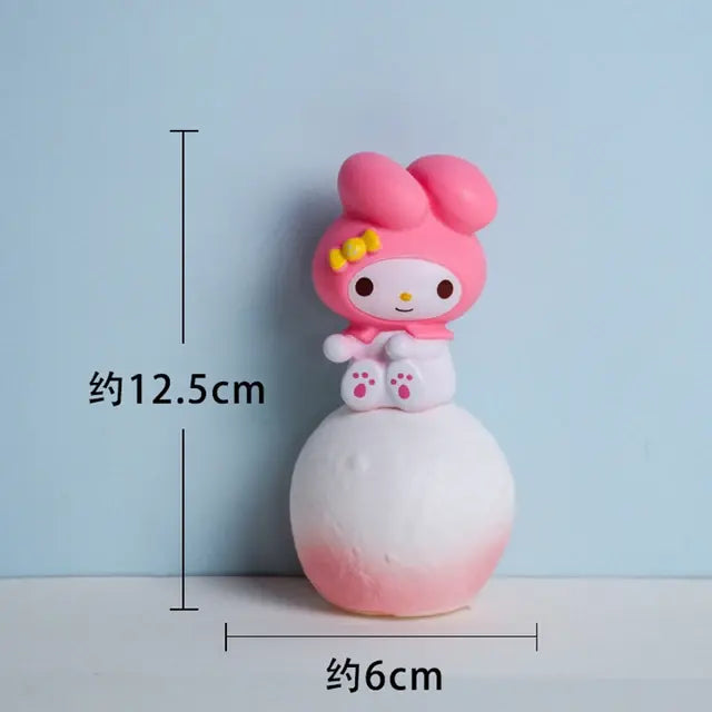 Small pink bunny figurine sitting on a round white-and-pink base, with measurement labels showing about 12.5 cm tall and about 6 cm wide, on a light blue background.