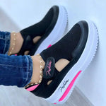 A pair of black low-top sneakers with white soles, worn by a person dressed in black joggers. The shoes feature red, white, and blue side stripes, “SPORT” lettering on the side panels, and the word “FASHION” near the heel.