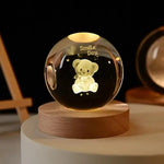 Glass crystal ball night light with a gold “cloud” and starry speckles inside, sitting on a wooden base against a dark background.