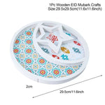 A white wooden decorative piece for Eid Mubarak with a crescent moon and star design. The background features colorful, traditional patterns with lanterns, and the dimensions are provided (29.5cm x 29.5cm or 11.6 inches).