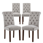 Four gray tufted dining chairs with wooden legs on a white background