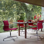 Outdoor setting with a wooden table and red chairs in a garden.