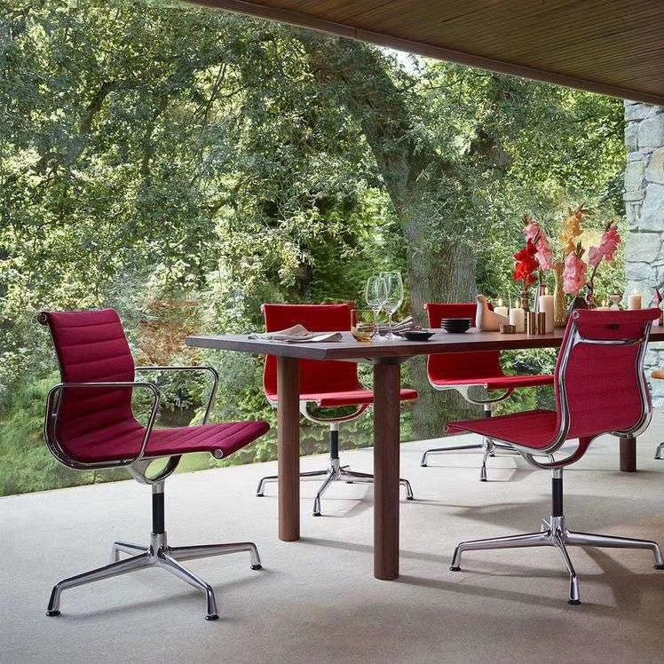 Outdoor setting with a wooden table and red chairs in a garden.