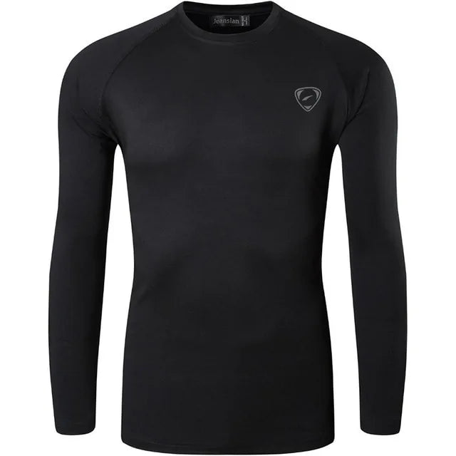 A sleek, light gray long-sleeve compression shirt with a crew neck, featuring a small logo on the upper left chest. The fabric appears smooth and stretchy, designed for athletic or casual wear.