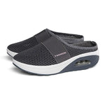A pair of gray breathable mesh slip-on mule sneakers with wide elastic straps across the top and cushioned white-and-gray platform soles. The shoes feature an open-back design, visible air-cushion detailing at the heel, and “FASHION” printed on the side strap, shown against a plain light gray background.