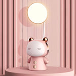 Cute pink bear-shaped desk lamp with a round glowing light on a curved stem, sitting on a circular tabletop against a pink striped wall.