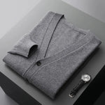 A neatly fold shirt on a black  surface with a black leather wrist-watch beside it