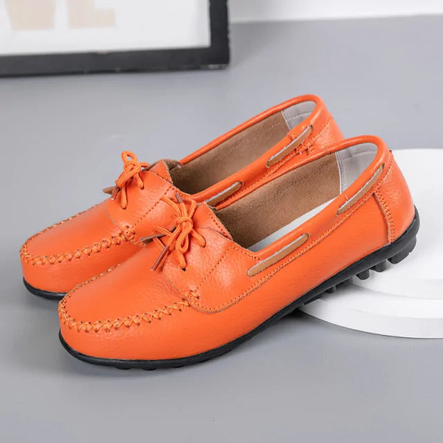 Orange leather-style loafers with lace tie detail, hand-stitched seams, and black driving sole.
