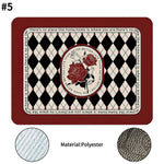 Rectangular polyester mat with a deep red border, black and cream diamond pattern, and a central circular rose motif, surrounded by the text “there’s no place like home,” with fabric texture close-up details shown.