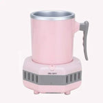 Pink electric heating mug with a metal-lined cup and gray handle, sitting on a matching pink-and-gray base with ventilation slots and an “ON/OFF” button.