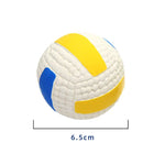 A product image of a small textured mini volleyball on a white background, colored white with yellow and blue curved panels. A measurement line underneath indicates the ball is 6.5 cm wide.
