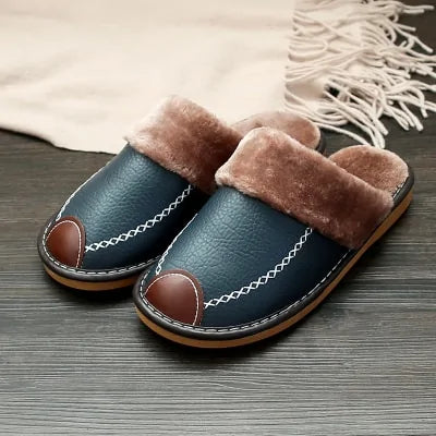 A pair of cozy brown indoor slippers with dark brown faux fur lining, displayed on a dark wooden floor.