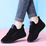 A pair of stylish mesh sneakers worn with jeans. The shoes feature colorful embroidered details The sneakers have a sleek, breathable design and a casual, trendy aesthetic.