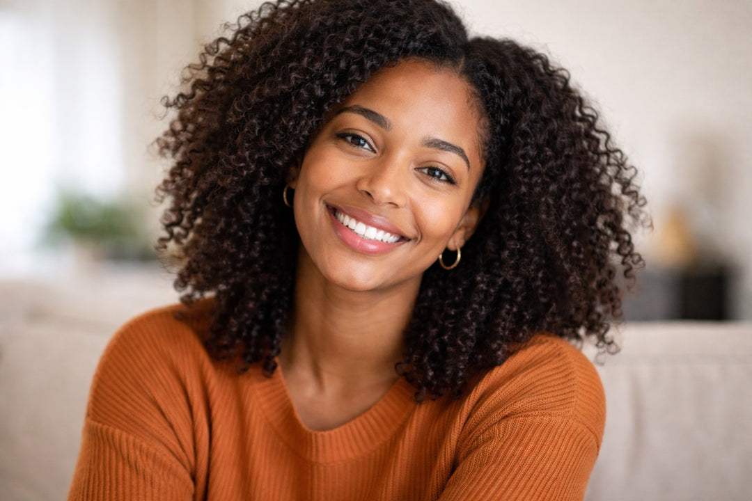 Woman with curly hair wearing an orange sweater in a living room setting