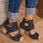 A close-up view of a person wearing stylish beige cut-out heeled sandals with ankle straps and decorative perforations, paired with cuffed blue denim jeans on a wooden floor.