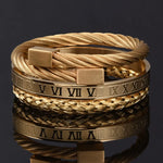 A set of three gold bracelets stacked together, including a twisted rope design and a flat band with Roman numeral markings.