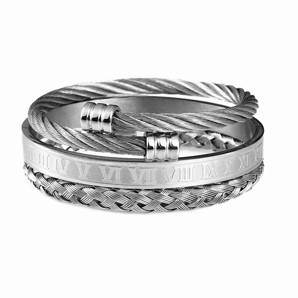 Silver-tone multi-layer cable cuff bracelet with twisted wire bands, a braided section, and a central ring engraved with Roman numerals, shown on a white background.
