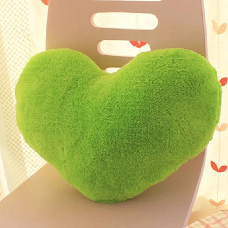 Soft, plush heart-shaped pillow in bright green resting on a chair, with a patterned background.