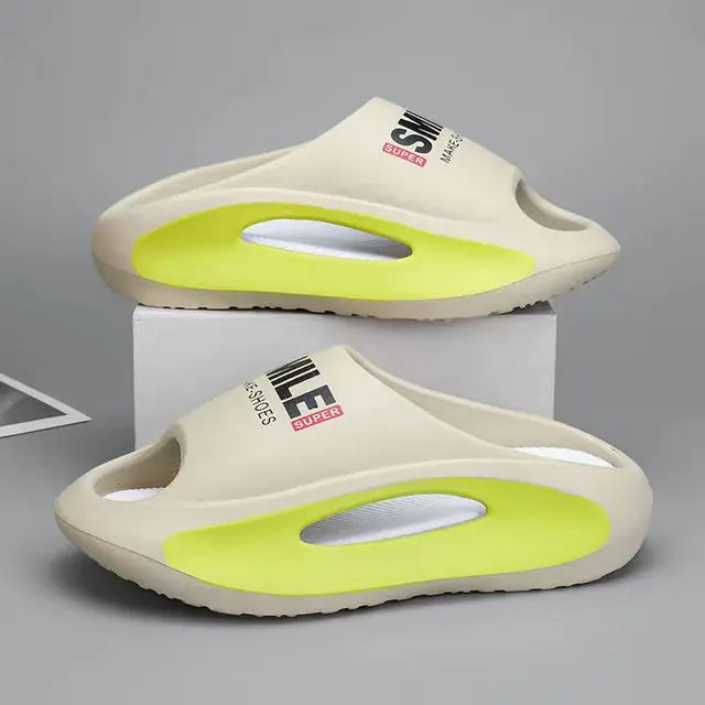A pair of stylish black slip-on sandals with purple cushioned insoles, featuring cutout designs on the sides and toes, displayed on a white surface next to stacked books.