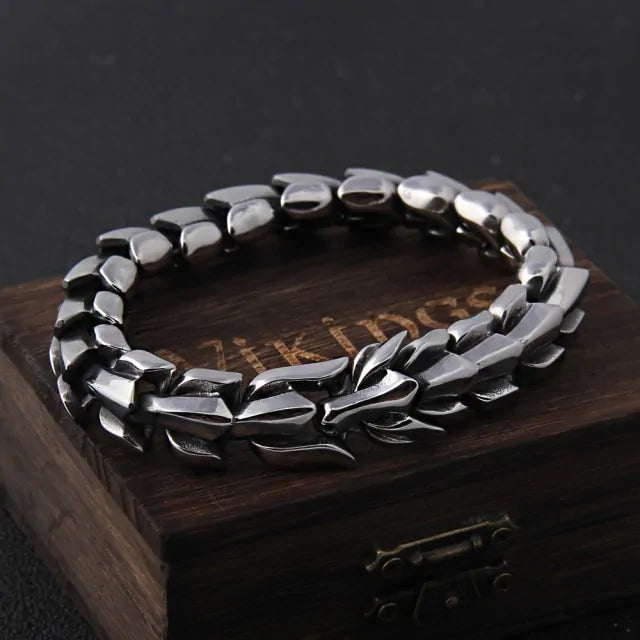 Dark metal chain-link bracelet resting on a wooden box against a gray background.