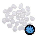 A collection of small white pebbles, some with a smooth, translucent appearance. A portion of the pebbles is shown glowing blue in the inset image, indicating they may have a glow-in-the-dark effect.