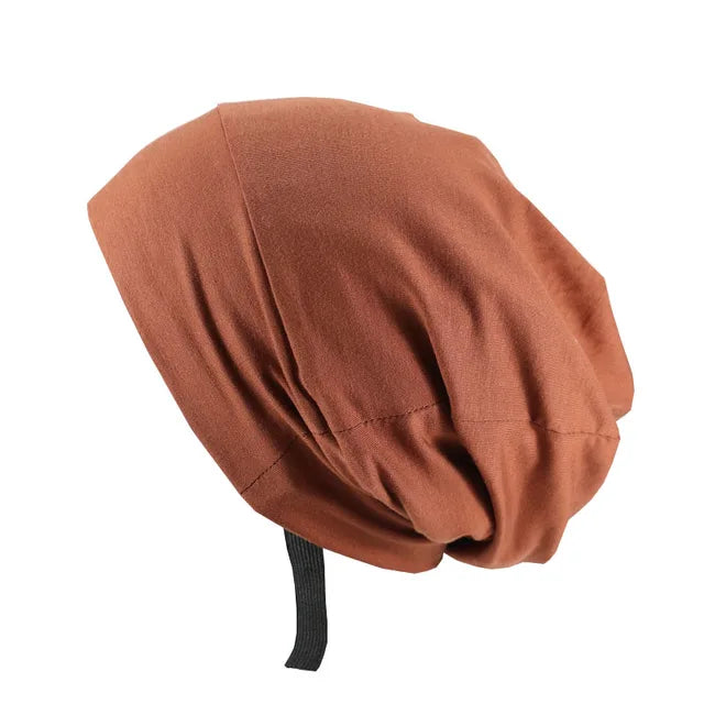 A brown slouchy beanie hat with a loose fit and an adjustable black strap at the back.