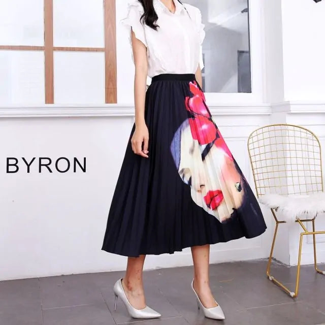 Pleated midi skirt with a gradient design, transitioning from dark black at the waistband to a soft blush pink at the hem, hanging on a black clothing rack next to a vintage-style camera.