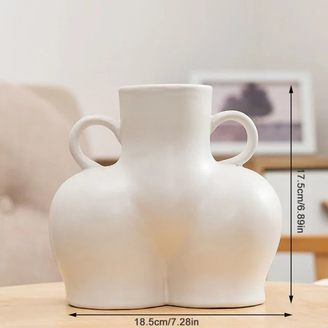 White abstract ceramic vase with a sculptural body-shaped design and twin loop handles.
