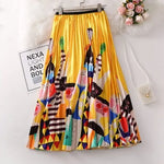 Pleated midi skirt with a gradient design, transitioning from dark black at the waistband to a soft blush pink at the hem, hanging on a black clothing rack next to a vintage-style camera.
