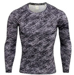 A long-sleeved athletic compression shirt with a gray, black, and white camouflage pattern on the front and sleeves. The shirt has black side panels and raglan-style sleeves, giving it a sporty and fitted design. The fabric appears to be stretchy and moisture-wicking, suitable for workouts or outdoor activities.