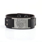 Black leather cuff bracelet with snap-button closure and rivet details, featuring a rectangular silver-tone metal plate engraved with a stylized wolf head.